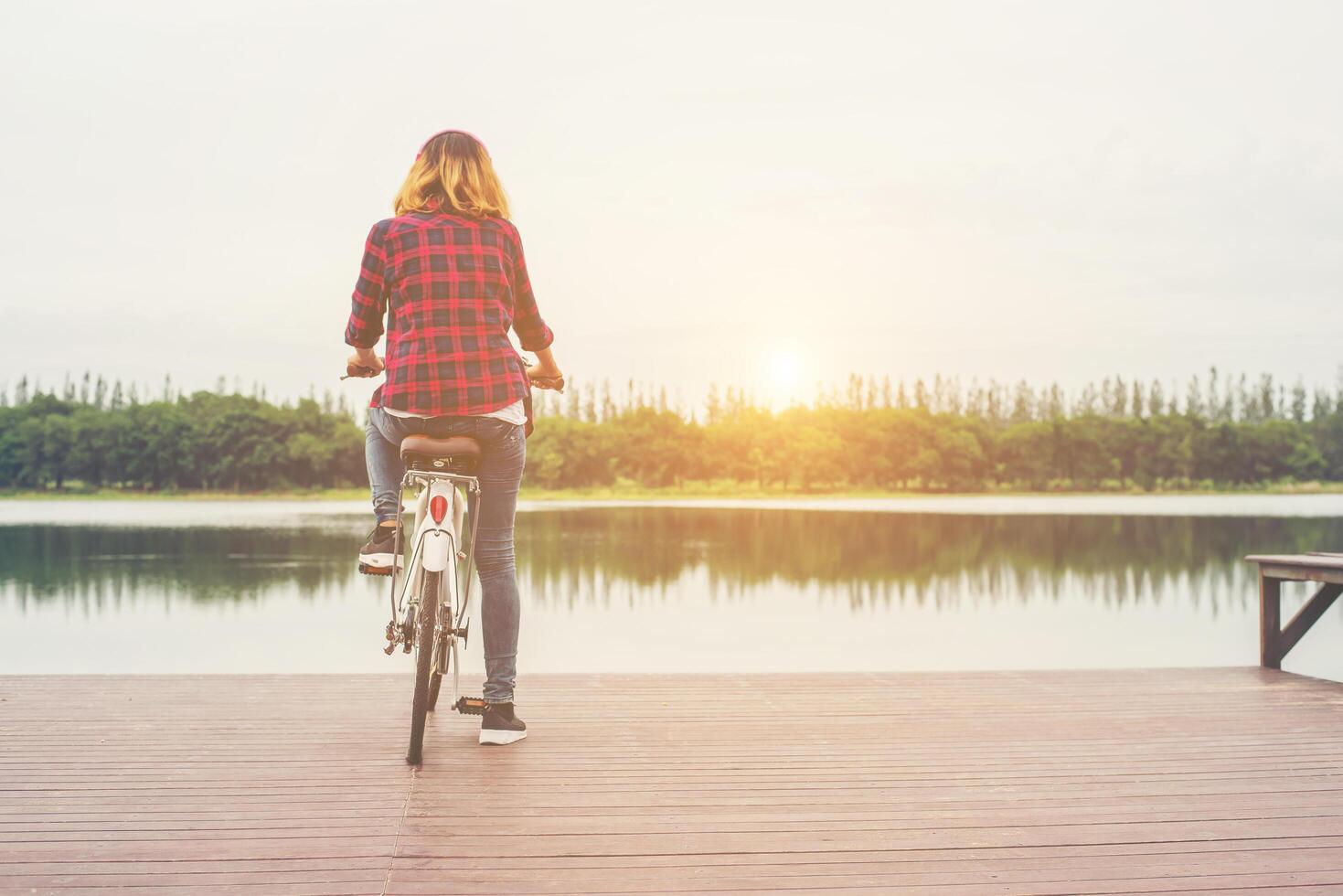 parte traseira da mulher jovem hippie andar de bicicleta com bicicleta em um píer, relaxando aproveite as férias de verão. foto