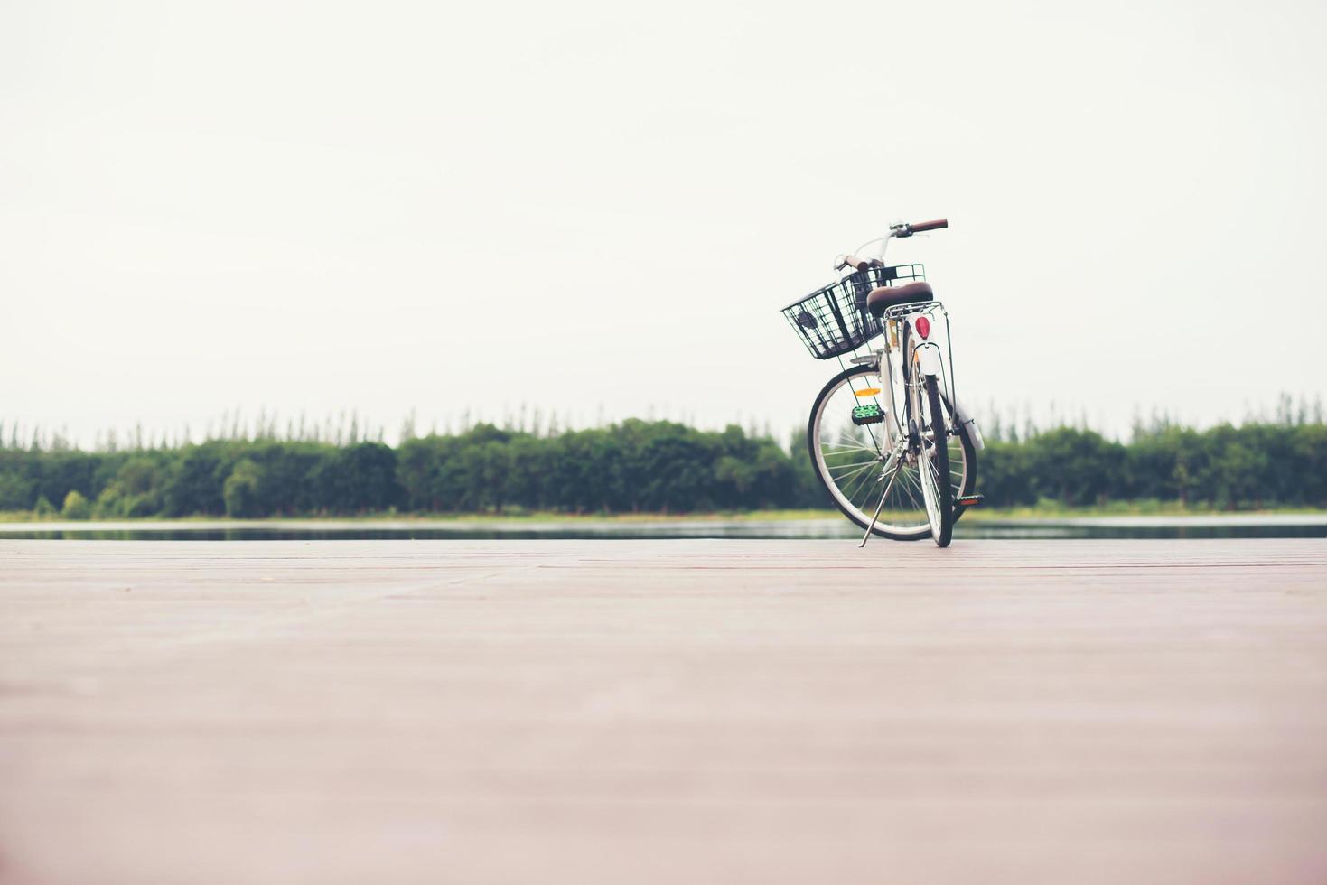vintage em tons de bicicleta com cesta no cais vazio, dia de verão. foto