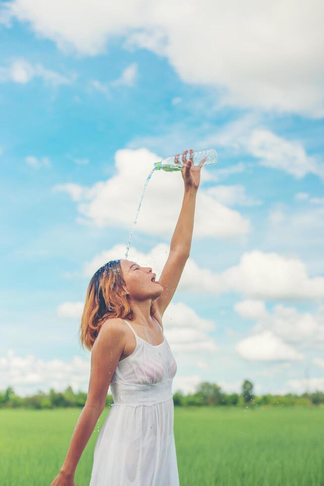 jovem no parque derrama sobre um rosto para se refrescar em pastagens desfrutar e vida feliz. foto