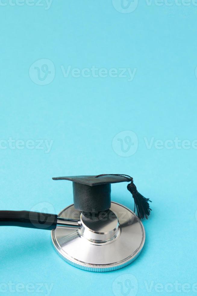 chapéu de formatura no estetoscópio, fundo azul com espaço de cópia. escola de medicina, educação em saúde ou formato vertical de conceito de diploma universitário de médico foto