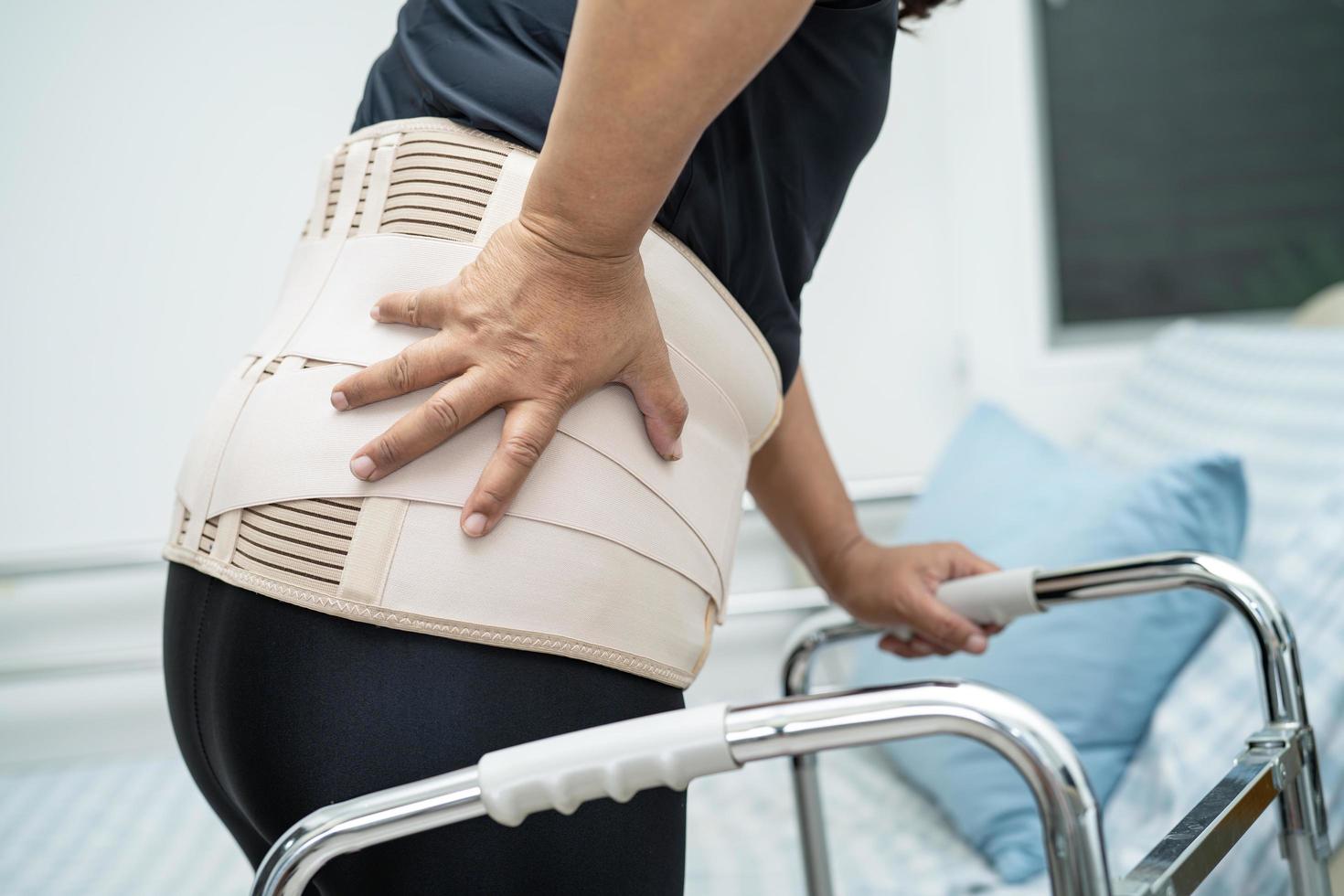 paciente senhora asiática usando cinto de suporte de dor nas costas para ortopédico lombar com andador. foto