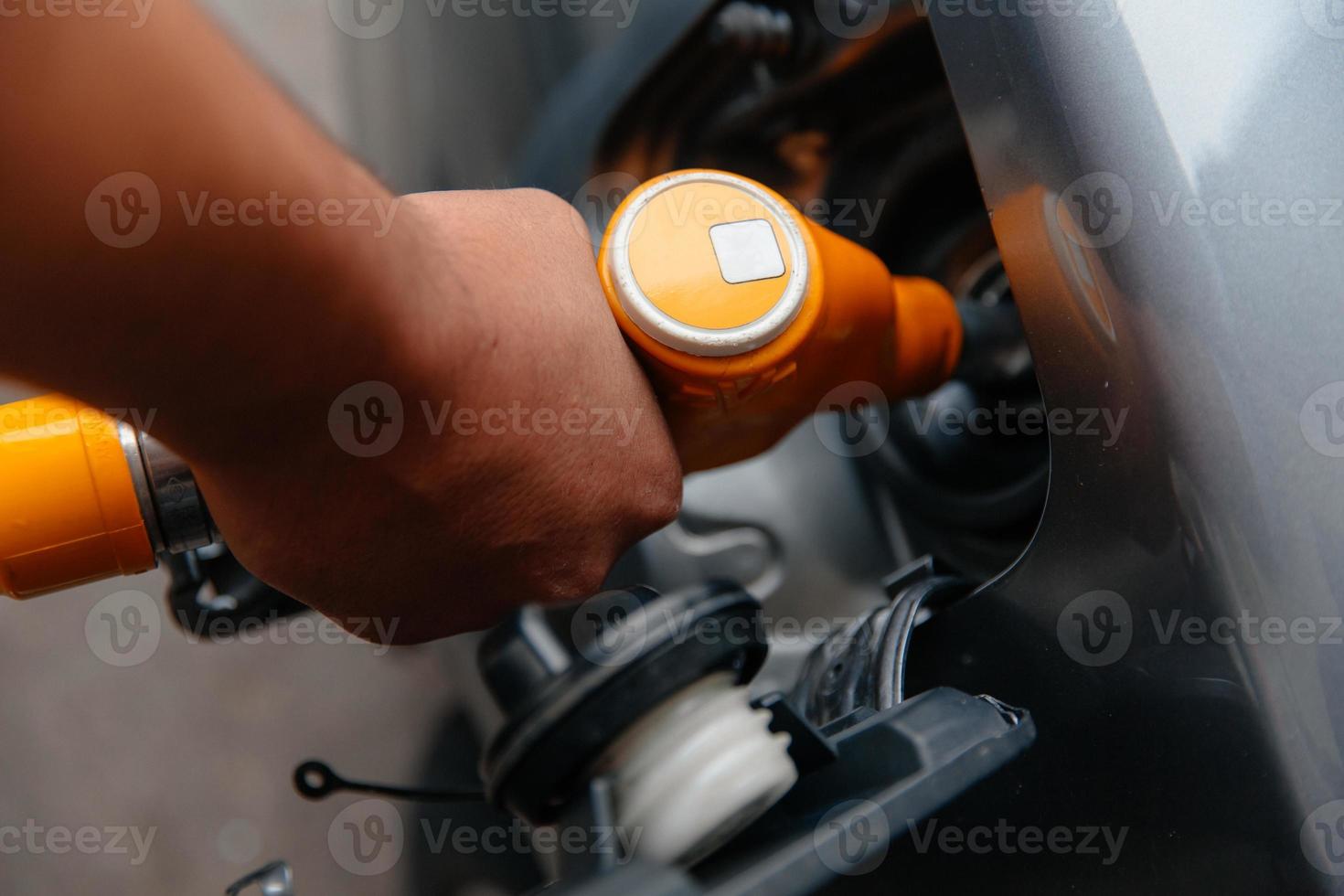 homem enchendo o combustível da gasolina no carro segurando a bomba. foto