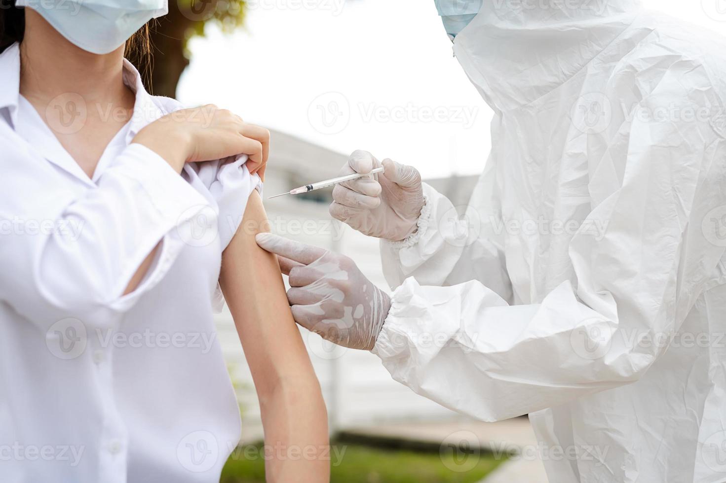 médico segurando a seringa antes de fazer a injeção no paciente com uma máscara médica. vacina covid-19 ou coronavírus foto