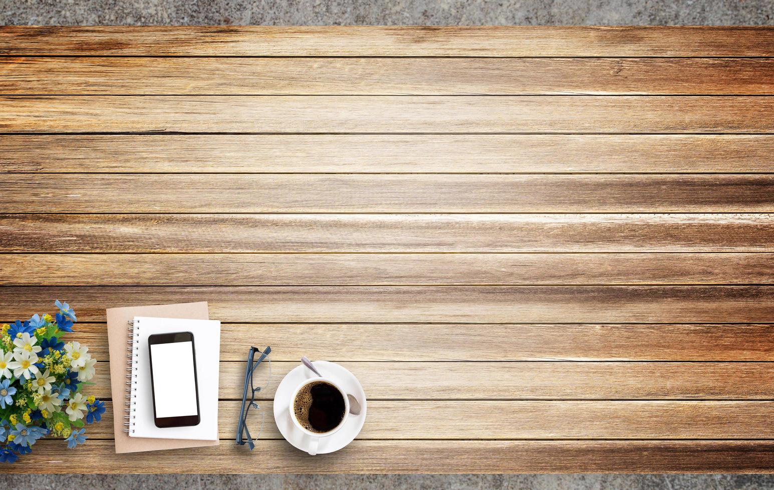 caderno em branco, telefone inteligente e xícara de café em madeira foto