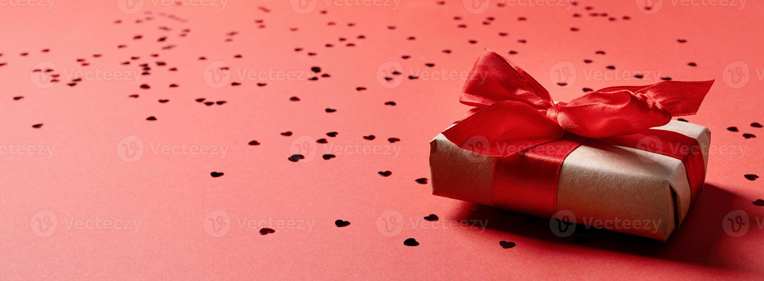 caixa de presente vermelha com uma fita para o dia dos namorados comemorando em fundo sólido vermelho com espaço de cópia foto