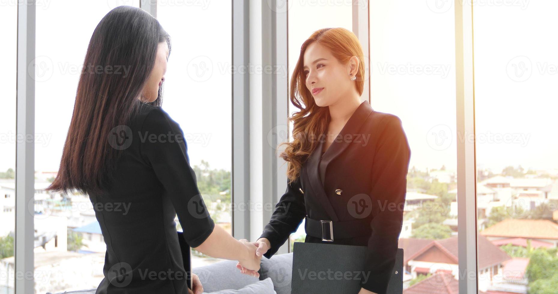 duas mulheres de negócios apertam a mão seu acordo para assinar contrato foto