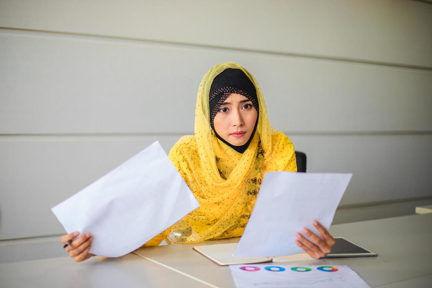 empresárias muçulmanas analisam documentos na mesa de escritório e têm diagrama financeiro gráfico trabalhando em segundo plano foto