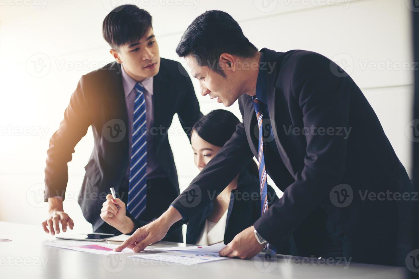 empresários trabalhando e apontando no diagrama financeiro gráfico e documentos de análise na mesa do escritório foto