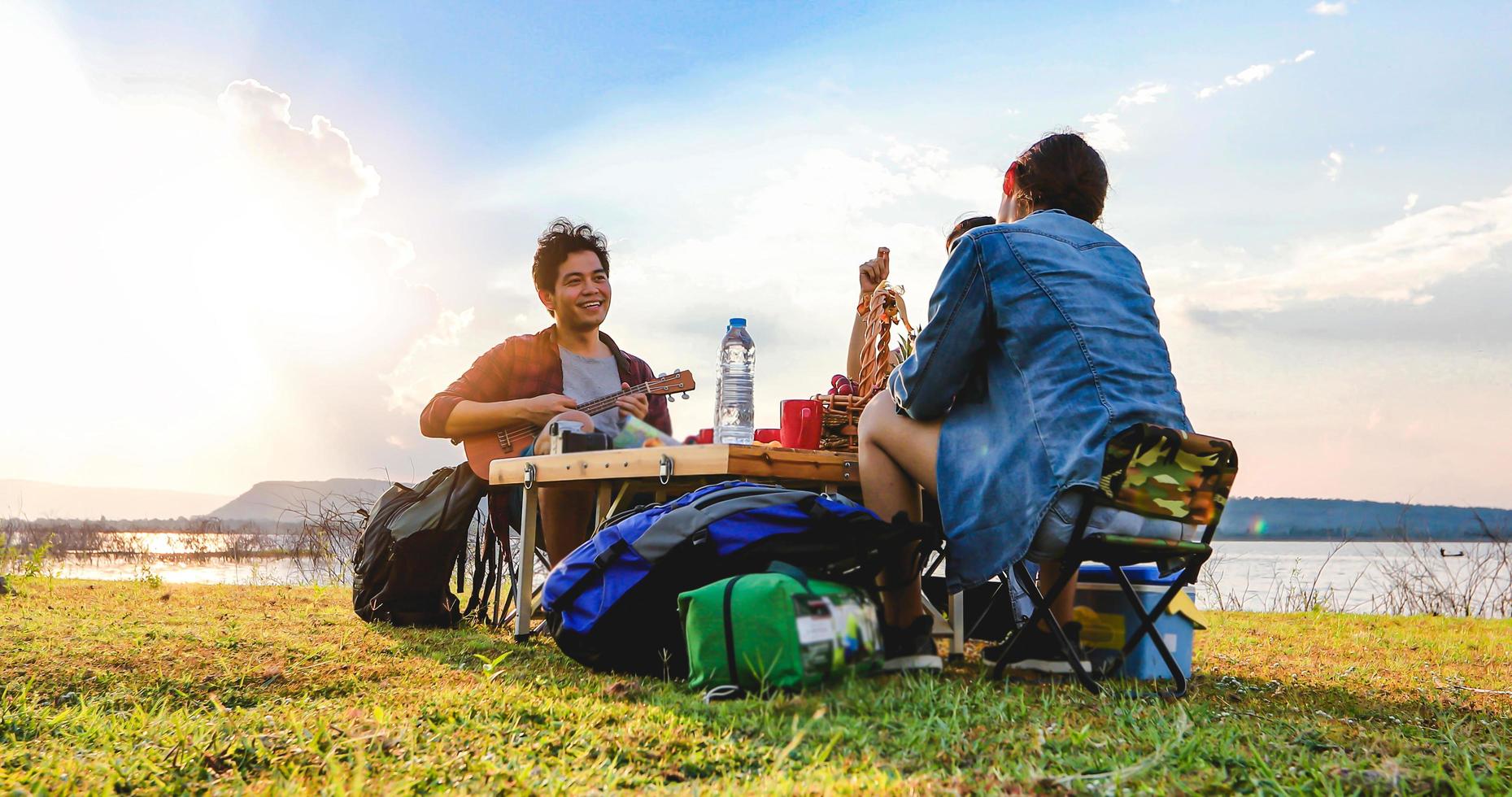 um grupo de amigos asiáticos tocando ukelele e passando o tempo fazendo um piquenique nas férias de verão. eles são felizes e se divertem nos feriados. foto