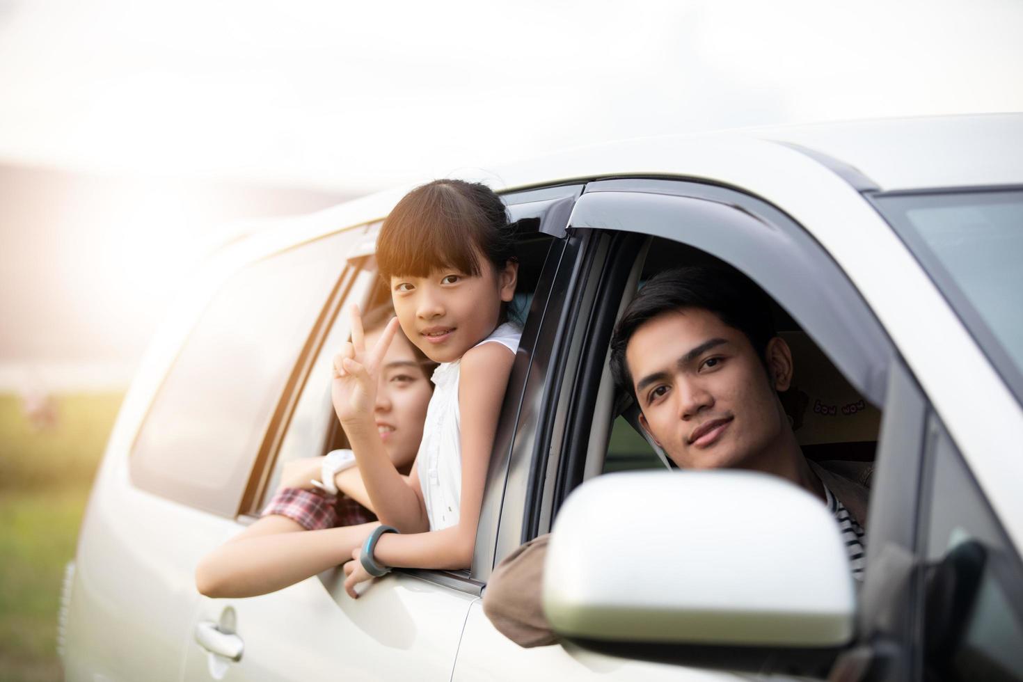 menina feliz com uma família asiática sentada no carro para aproveitar a viagem e as férias de verão em uma van de camping foto