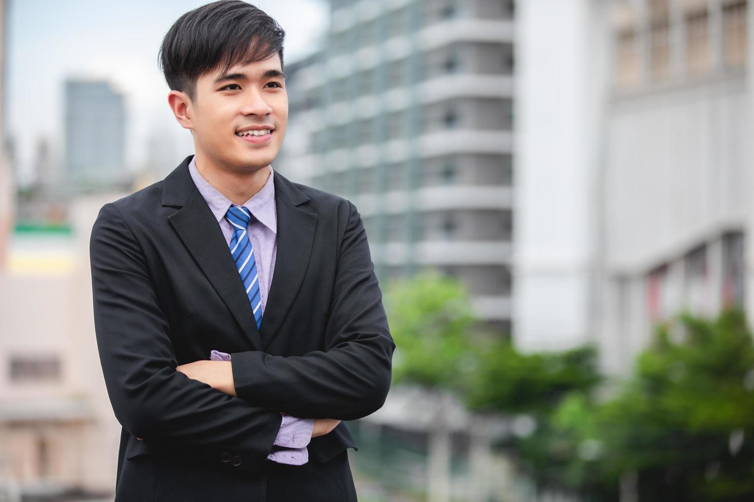 empresário bonito feliz em pé e sorrindo para o exterior foto