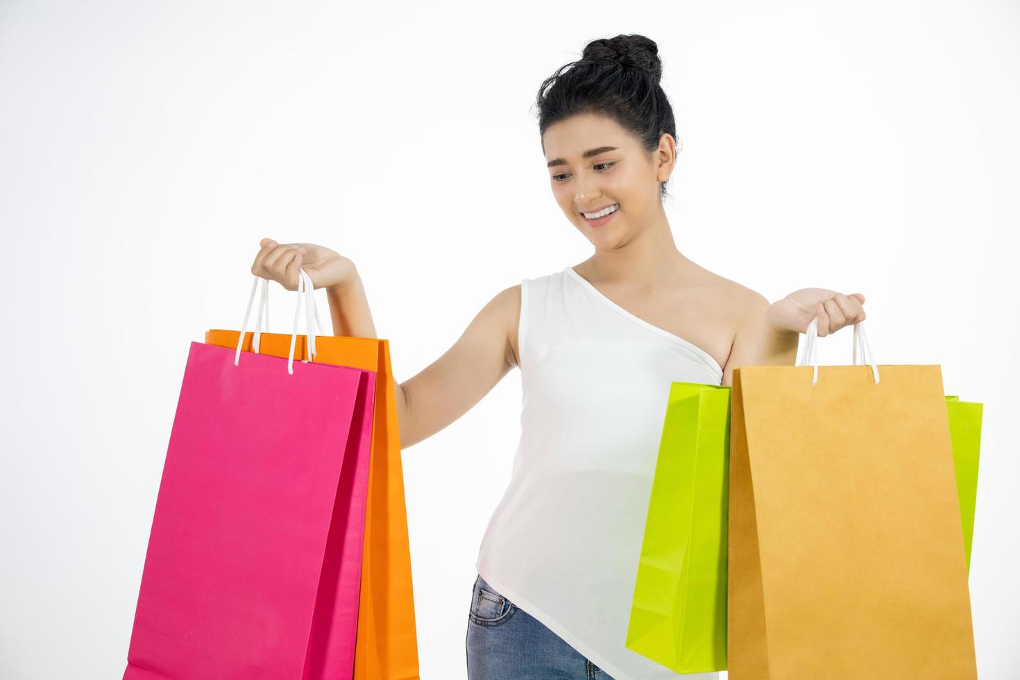 Linda garota asiática segurando sacolas de compras e sorrindo foto