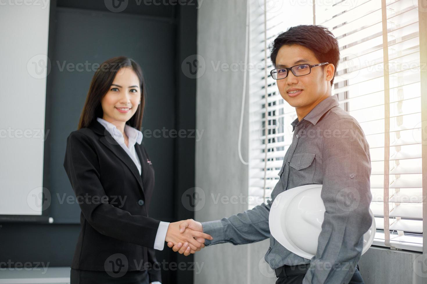 empresários asiáticos apertando as mãos e sorrindo concordando para assinar o contrato e encerrar uma reunião foto
