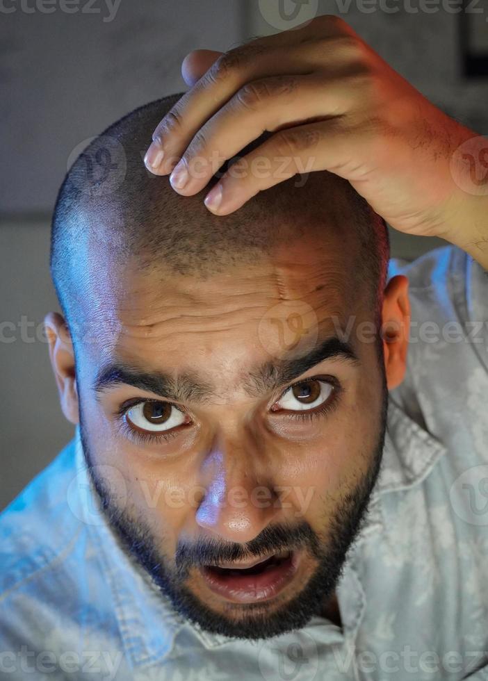 um jovem careca chocado na frente da câmera foto