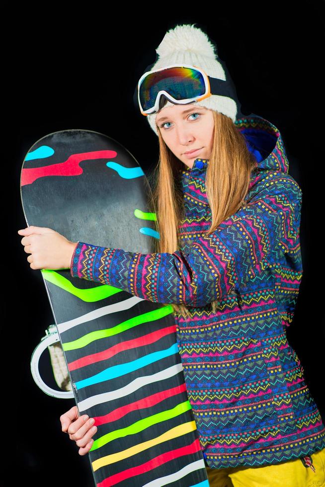 garota esportiva com olhos azuis com snowboard em fundo preto em estúdio foto