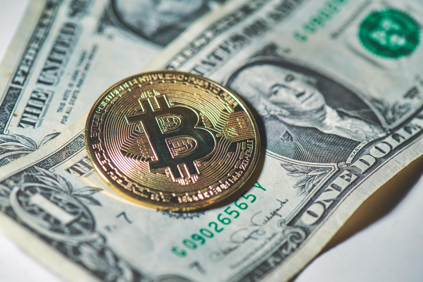 uma moeda de bitcoin descansando em dólares de papel americanos foto