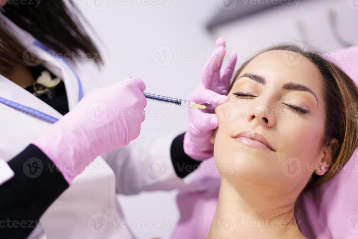 médico injetando ácido hialurônico nas maçãs do rosto de uma mulher como tratamento de rejuvenescimento facial. foto