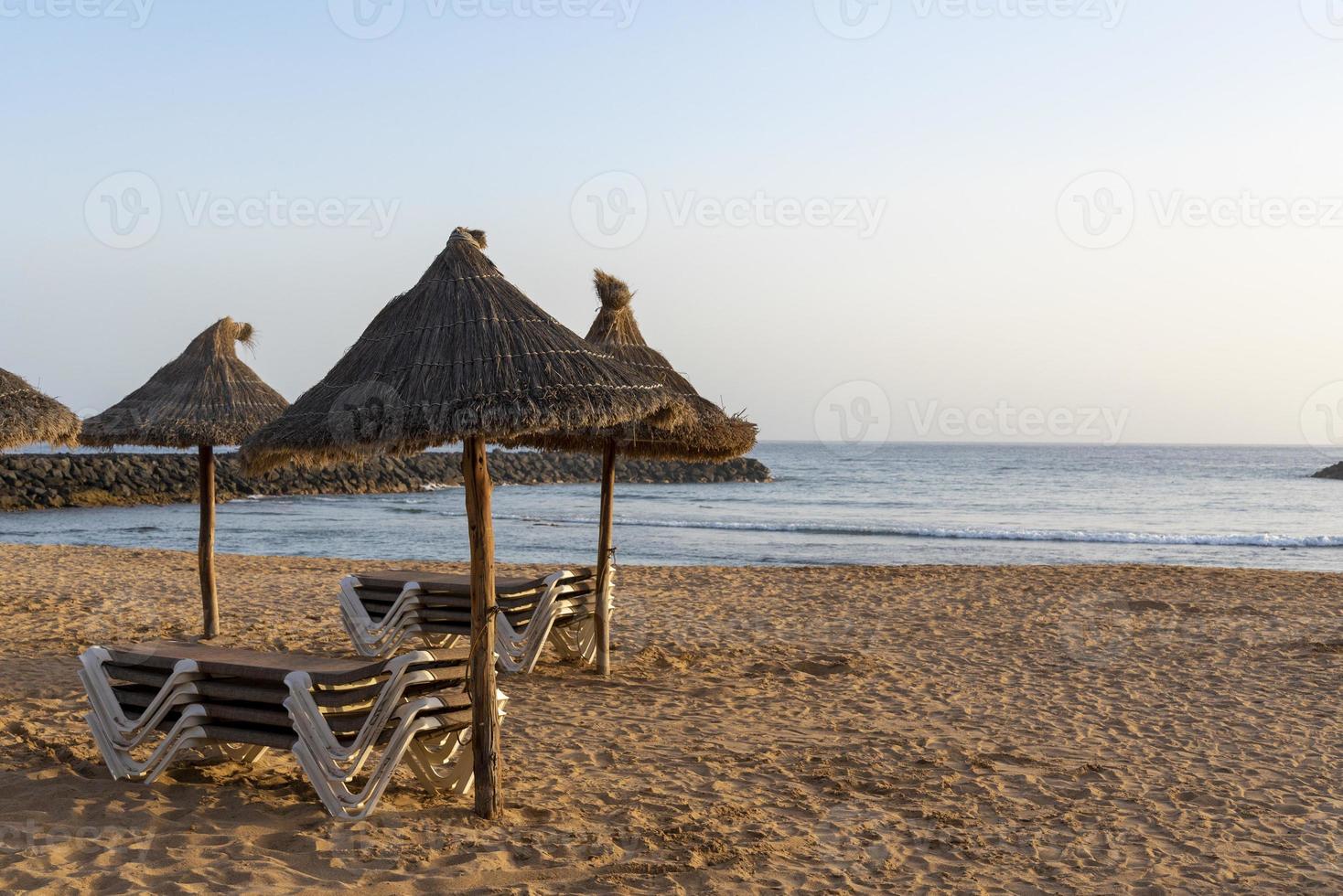 espreguiçadeiras vazias em uma praia tropical. espreguiçadeiras na praia de areia à beira-mar. férias de verão e conceito de férias para turismo. foto