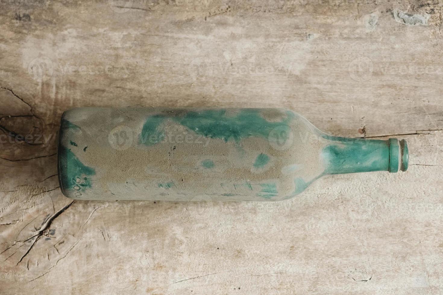 garrafa de vidro vazia na sujeira em um fundo de madeira. vista do topo. copiar, espaço vazio para texto foto