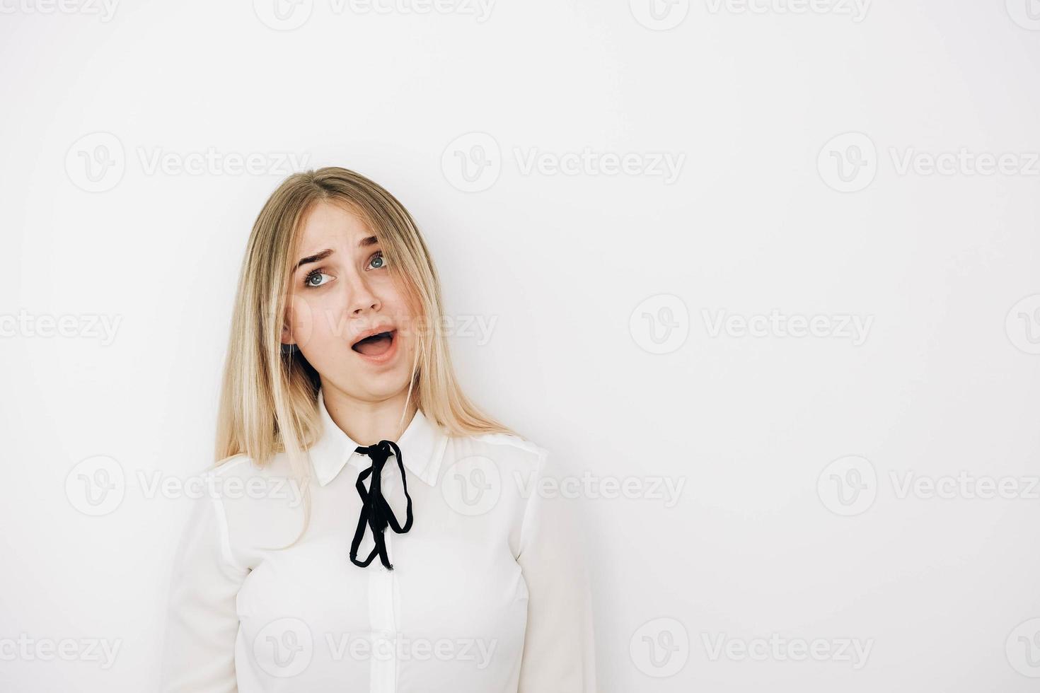 retrato mulher loira vestindo camisa branca elegante sobre fundo branco espantado e surpreso olhando para longe e abrindo a boca. cópia, espaço vazio para texto foto