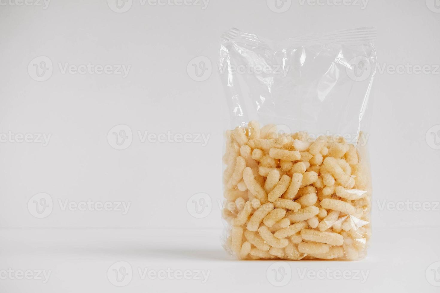 palitos de milho em um saco plástico em um fundo branco. lugar para o seu texto foto