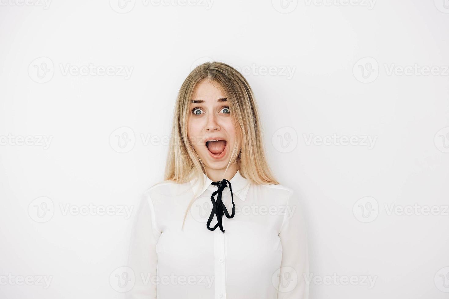 retrato mulher loira vestindo camisa branca elegante sobre fundo branco espantado e surpreso olhando para longe e abrindo a boca. cópia, espaço vazio para texto foto