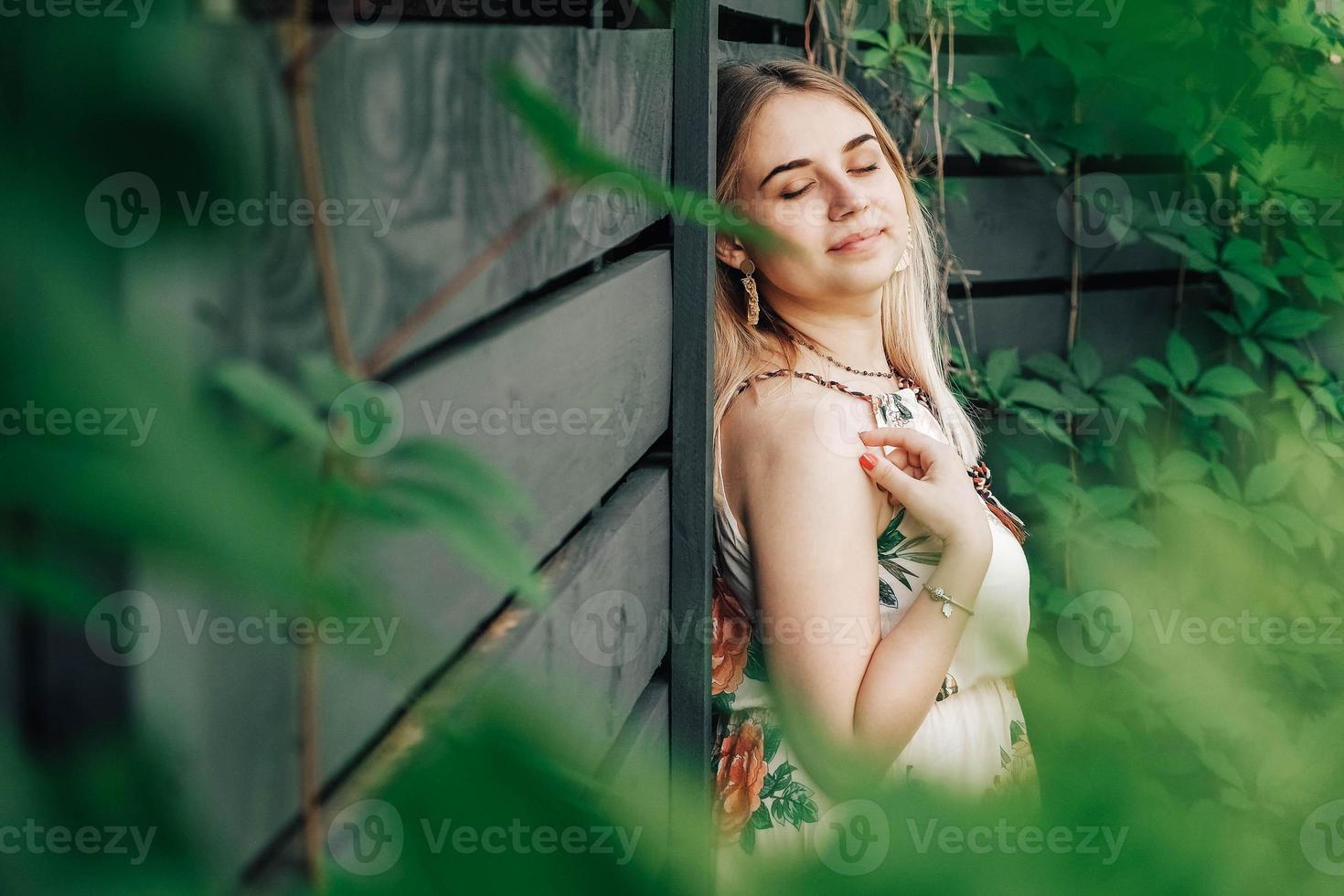 retrato de uma linda mulher loira com olhos fechados e beleza natural em um verde deixa árvores em um fundo de parede de madeira. copiar, espaço vazio para texto foto