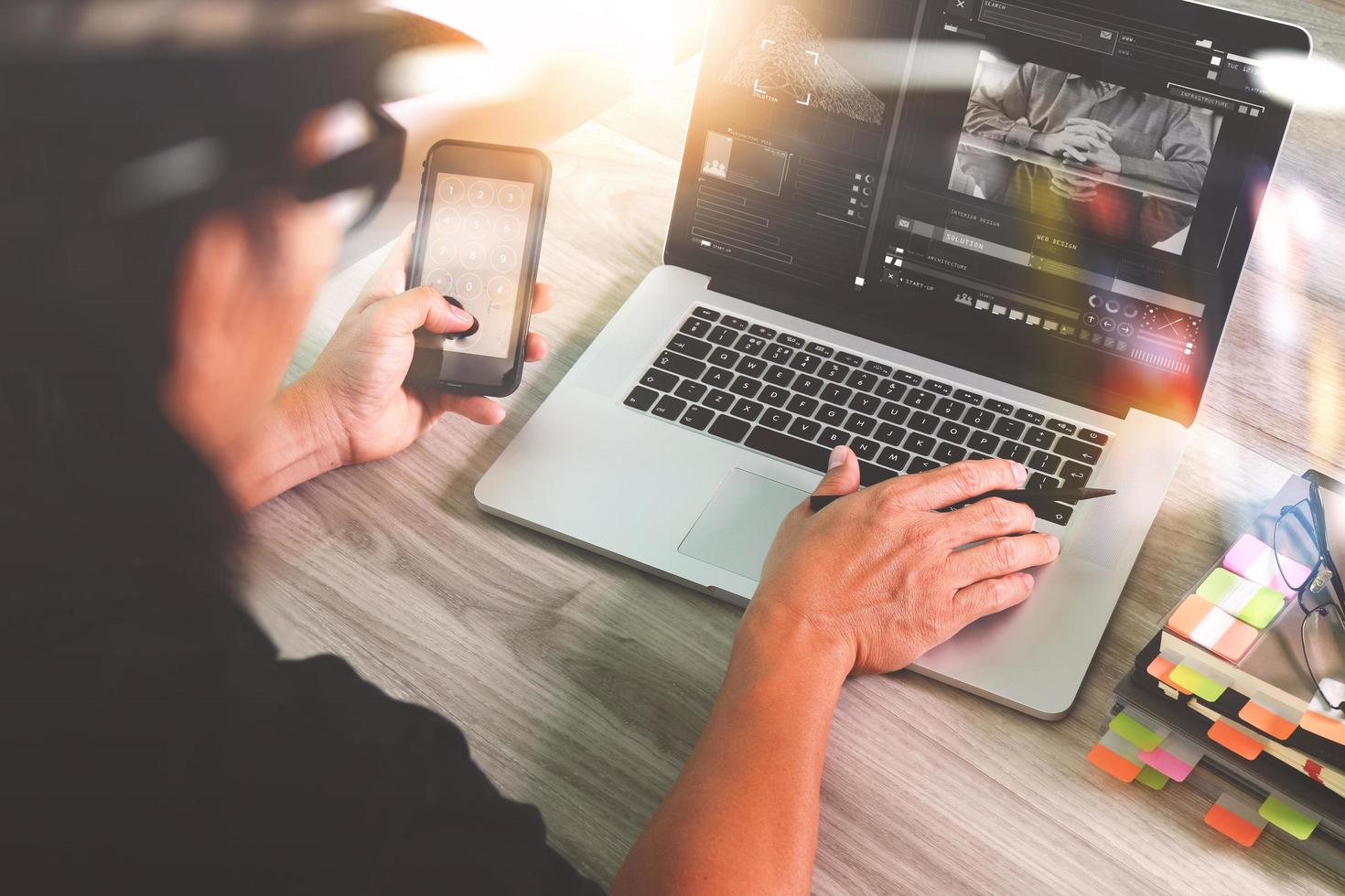 mão de designer participando de videoconferência com computador portátil e telefone inteligente na mesa no escritório foto