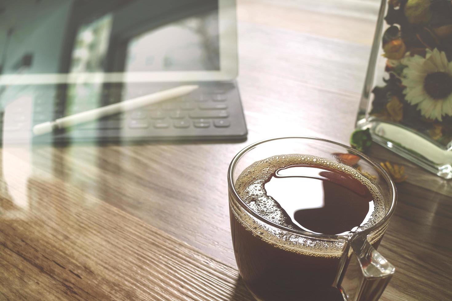 xícara de café ou chá e teclado inteligente dock de mesa digital, ervas de flores de vaso, caneta stylus na mesa de madeira, efeito de filtro foto