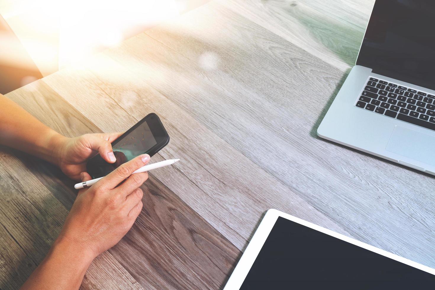 mão de empresário trabalhando com caneta stylus tablet digital smartphone e computador portátil. participando de videoconferência no escritório moderno. na mesa de madeira. vista de cima. efeitos de dupla exposição, minimalismo foto