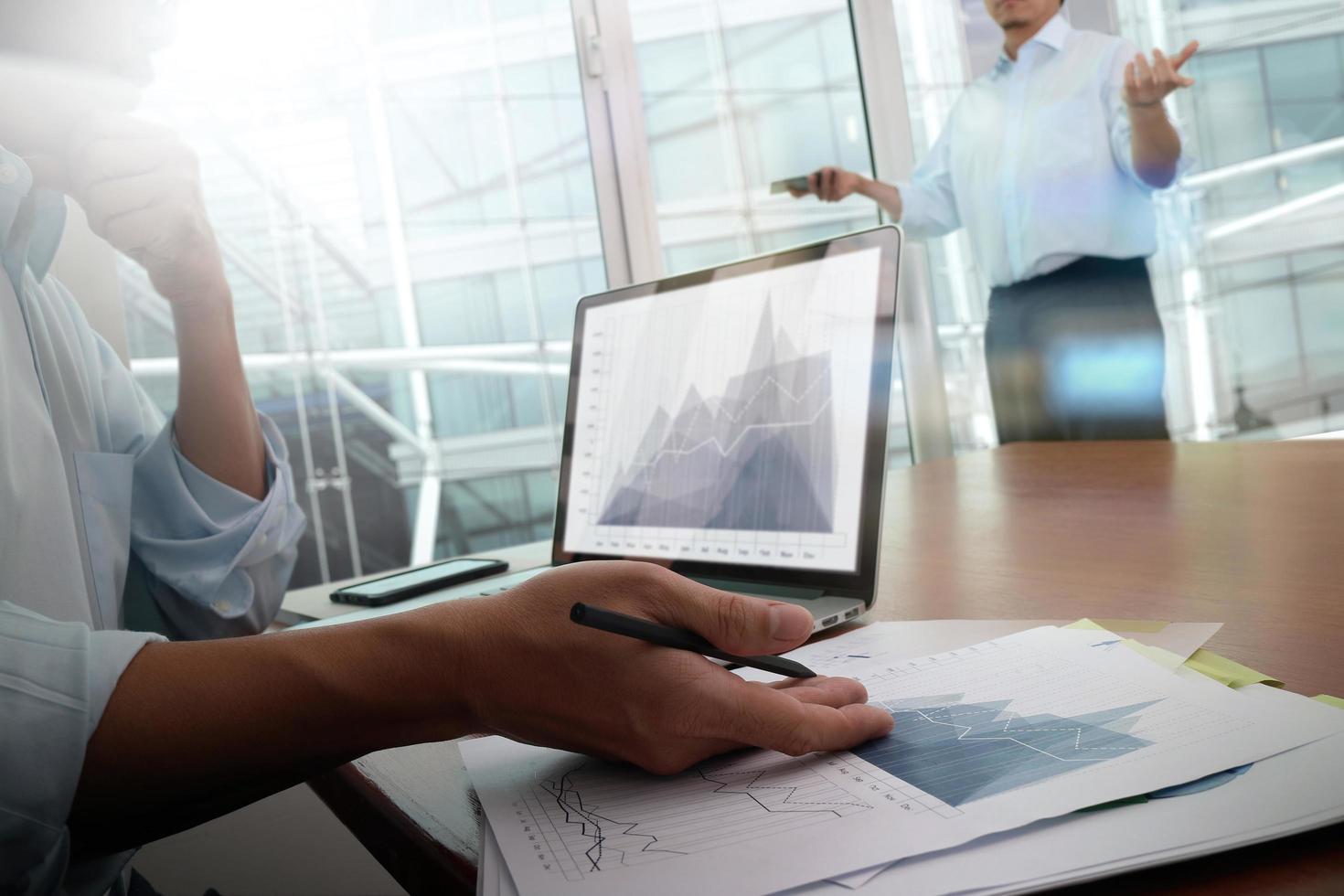 documentos de negócios na mesa de escritório com telefone inteligente e computador portátil e negócios gráficos com diagrama de rede social e dois colegas discutindo dados foto