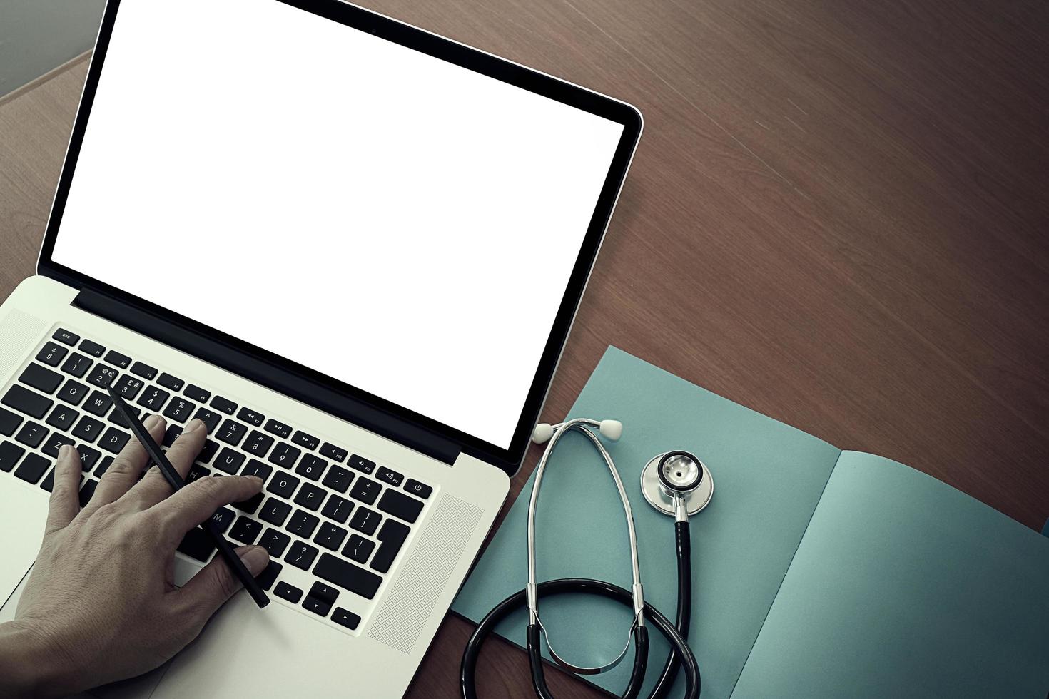 vista superior da mão do médico trabalhando com computador moderno e tela em branco na mesa de madeira como conceito médico foto