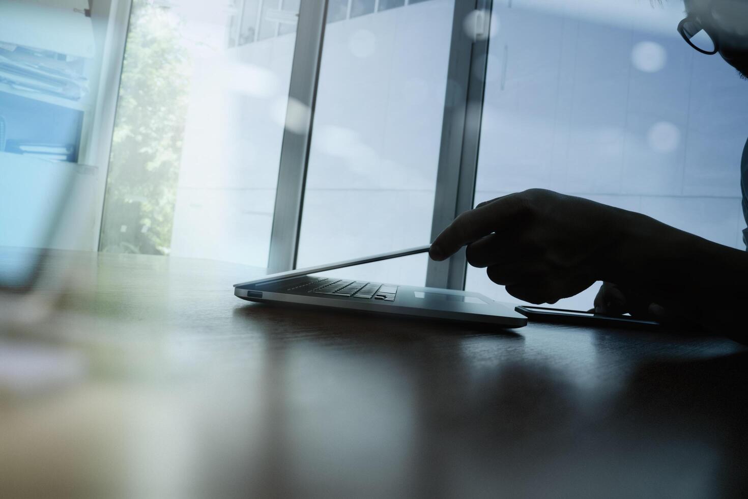 close-up da mão do homem de negócios trabalhando no computador portátil na mesa de madeira foto