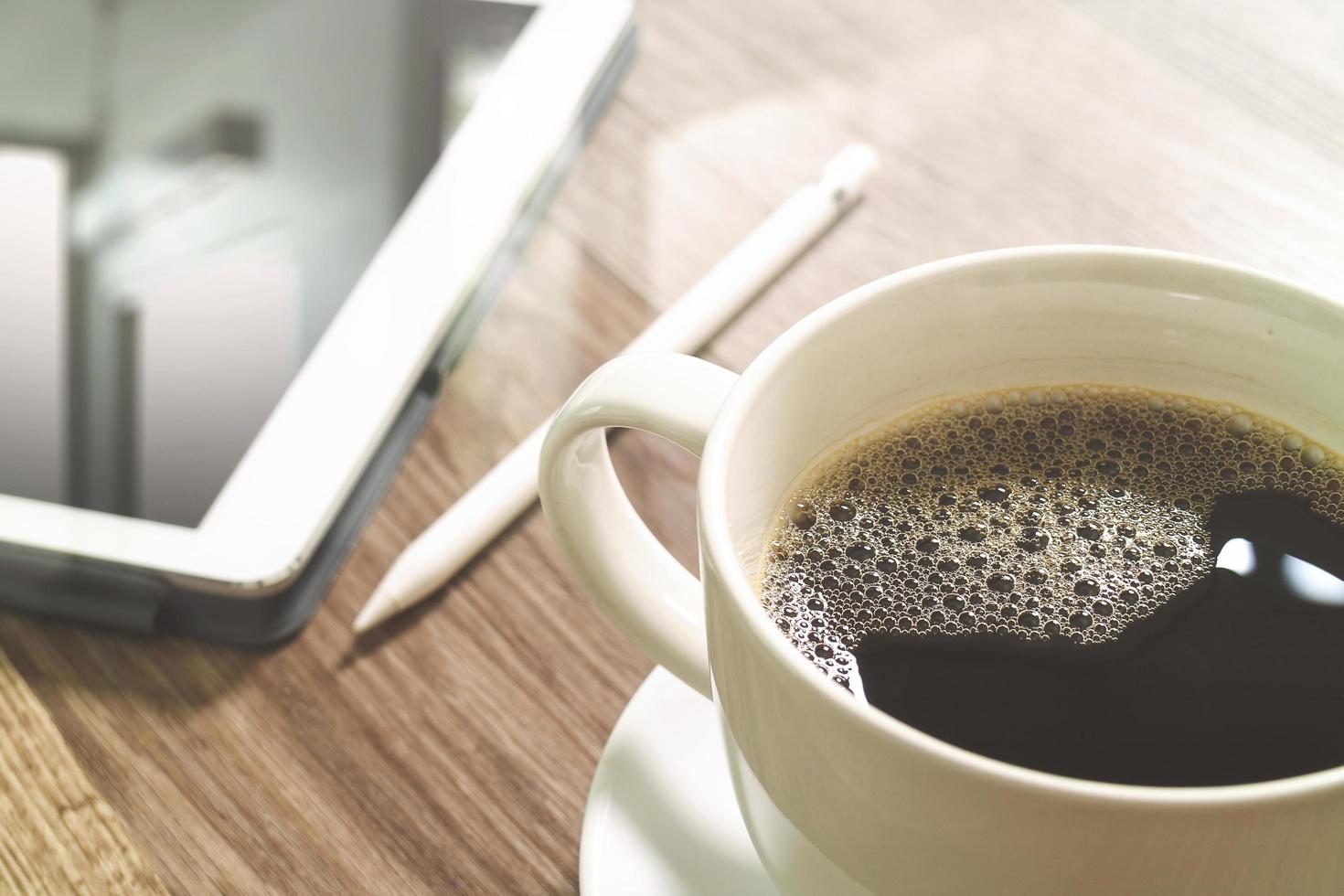 xícara de café e teclado inteligente dock de mesa digital, óculos, caneta stylus na mesa de madeira, efeito de filtro foto