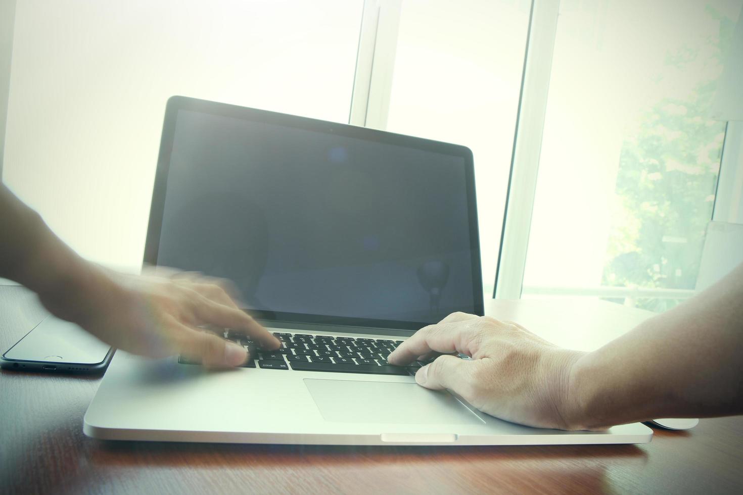 close-up da mão do homem de negócios, trabalhando no computador portátil de tela em branco na mesa de madeira como conceito foto