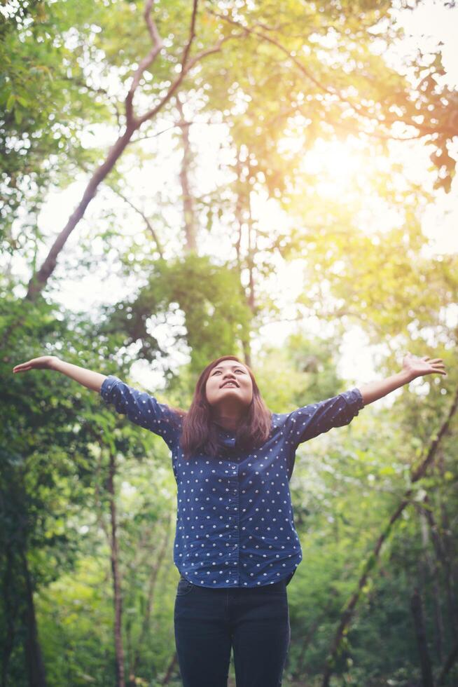 mulher jovem e atraente de pé em uma floresta, mãos espalhadas e desfrutar do ambiente natural refrescante. foto