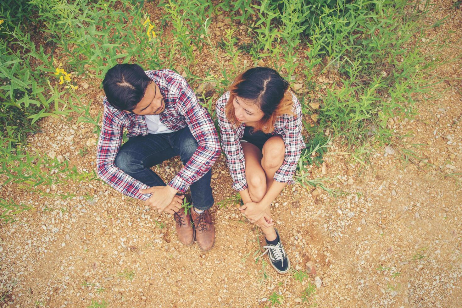 casal jovem hippie feliz sentado no campo amarelo, namorando aproveitando o tempo juntos. foto