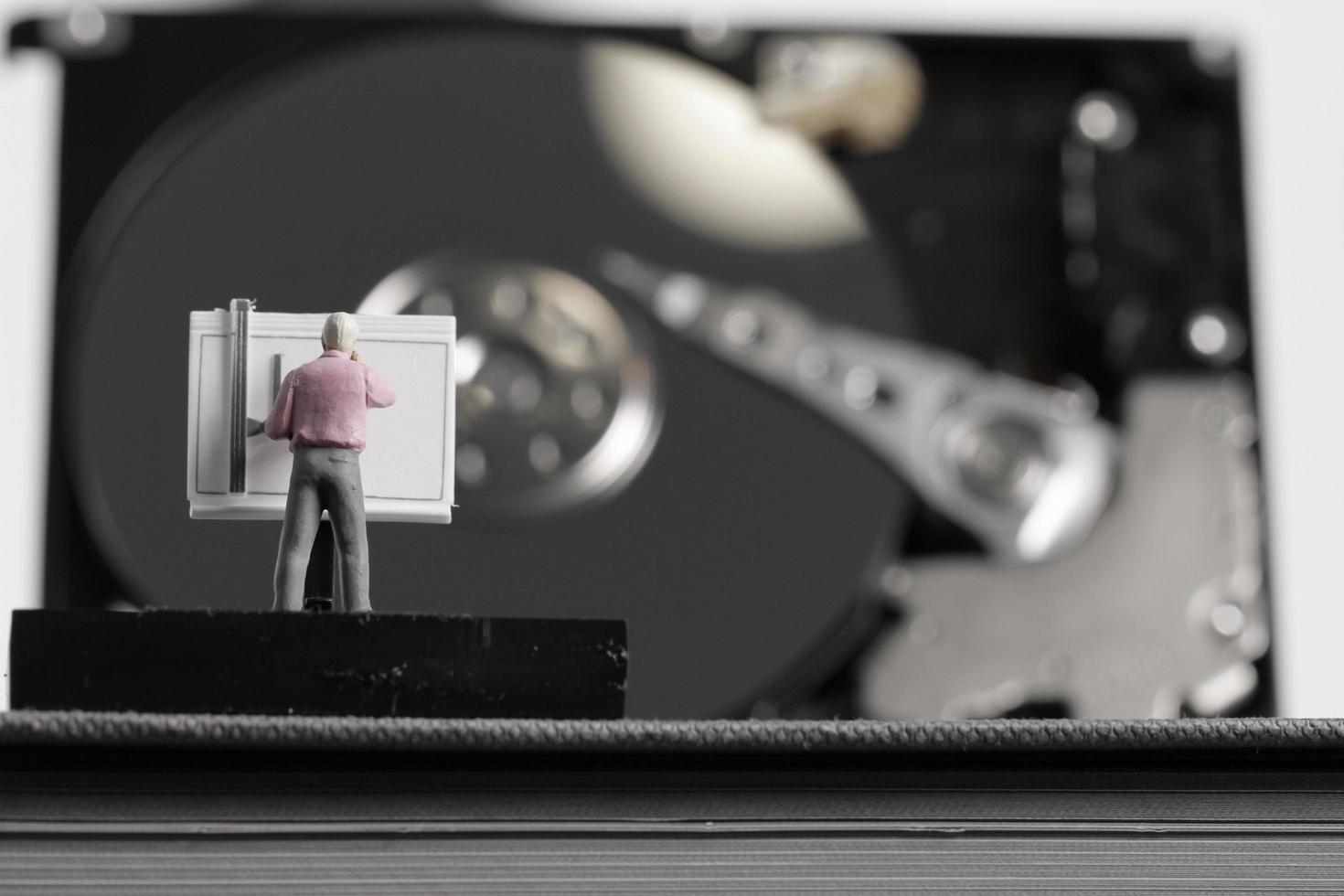 engenheiro em miniatura de conceito de big data trabalhando com mesa de desenho com fundo de disco rígido aberto foto