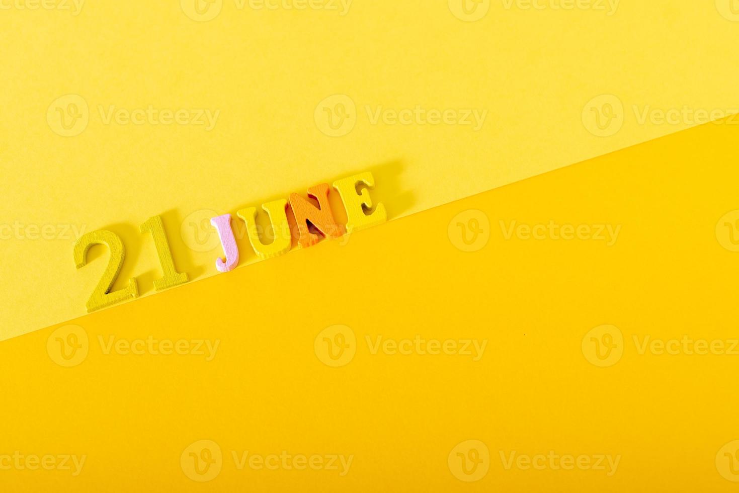 21 de junho, letras de madeira e números em um fundo amarelo. foto