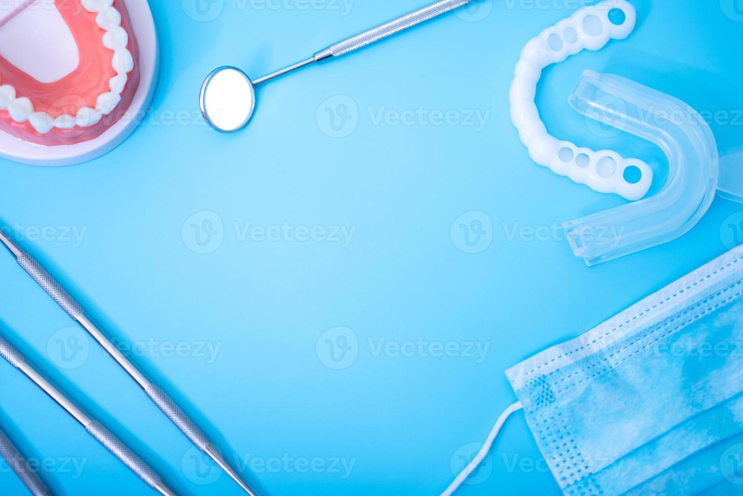 modelo de dentes com instrumentos odontológicos sobre fundo azul. foto