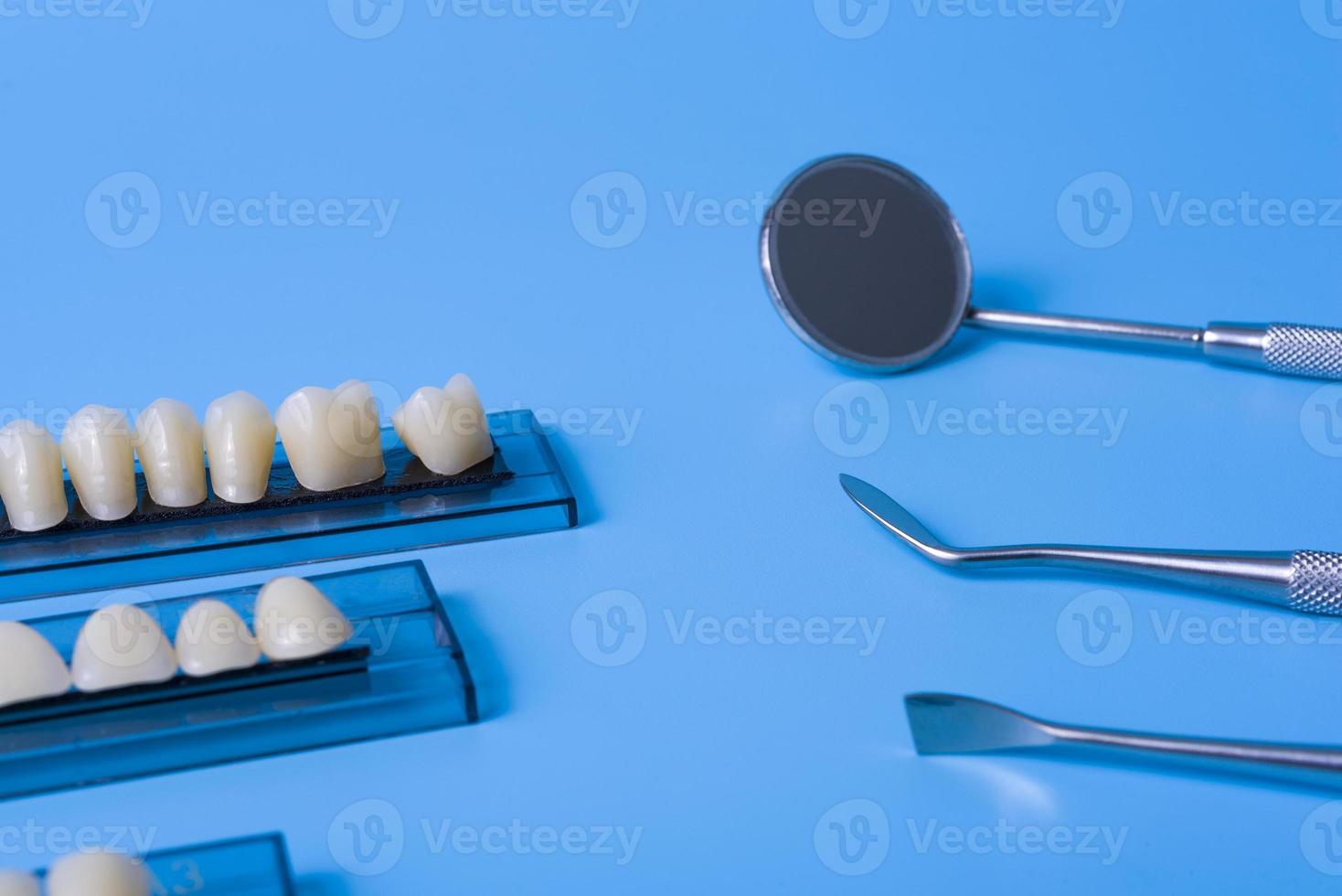 modelo de dentes com ferramentas dentárias em fundo azul foto