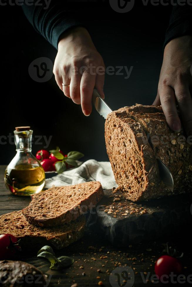 mãos femininas cortando pão multigrãos caseiro foto