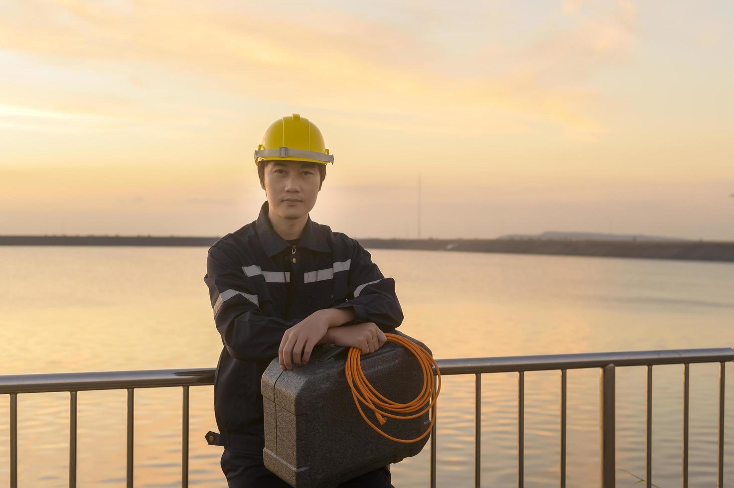 um engenheiro masculino usando um capacete protetor ao pôr do sol. foto