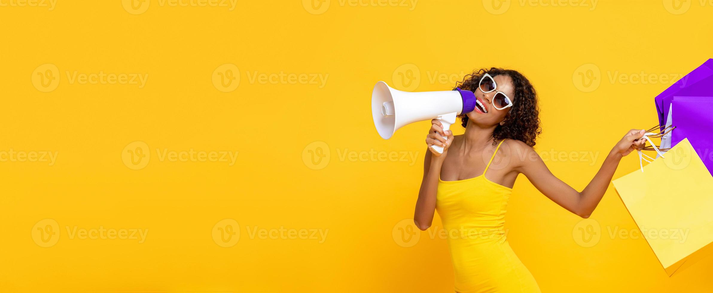 mulher bonita feliz com sacolas de compras e megafone em fundo de banner amarelo colorido isolado para conceitos de venda e desconto foto