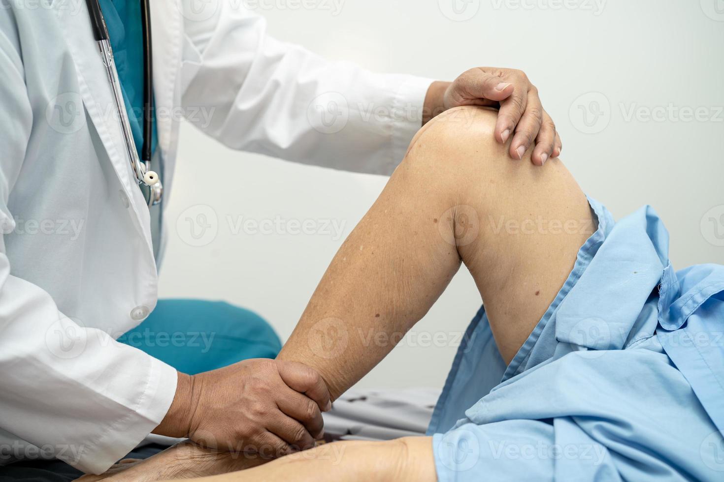 Médico fisioterapeuta examinando, massageando e tratando o joelho e a perna do paciente sênior no hospital de enfermagem da clínica médica ortopedista. foto