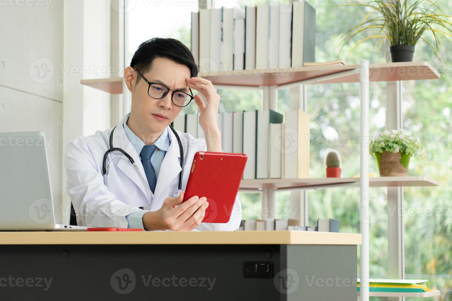 médico lendo o registro do paciente do tablet digital no escritório do hospital foto