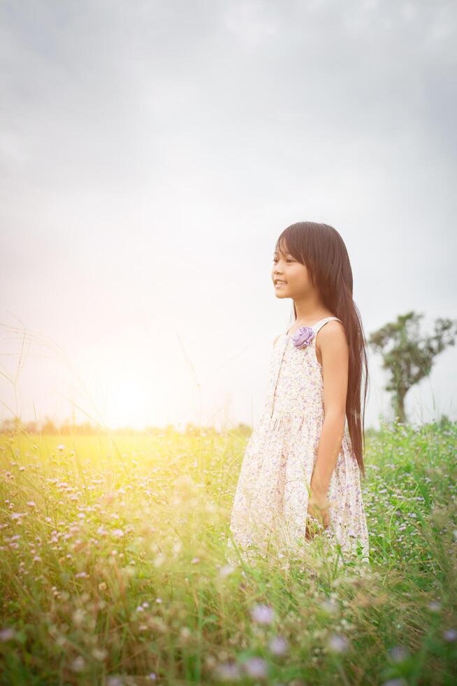 menina asiática bonitinha andando entre o campo de flores roxas, liberdade desfrutar do conceito. foto