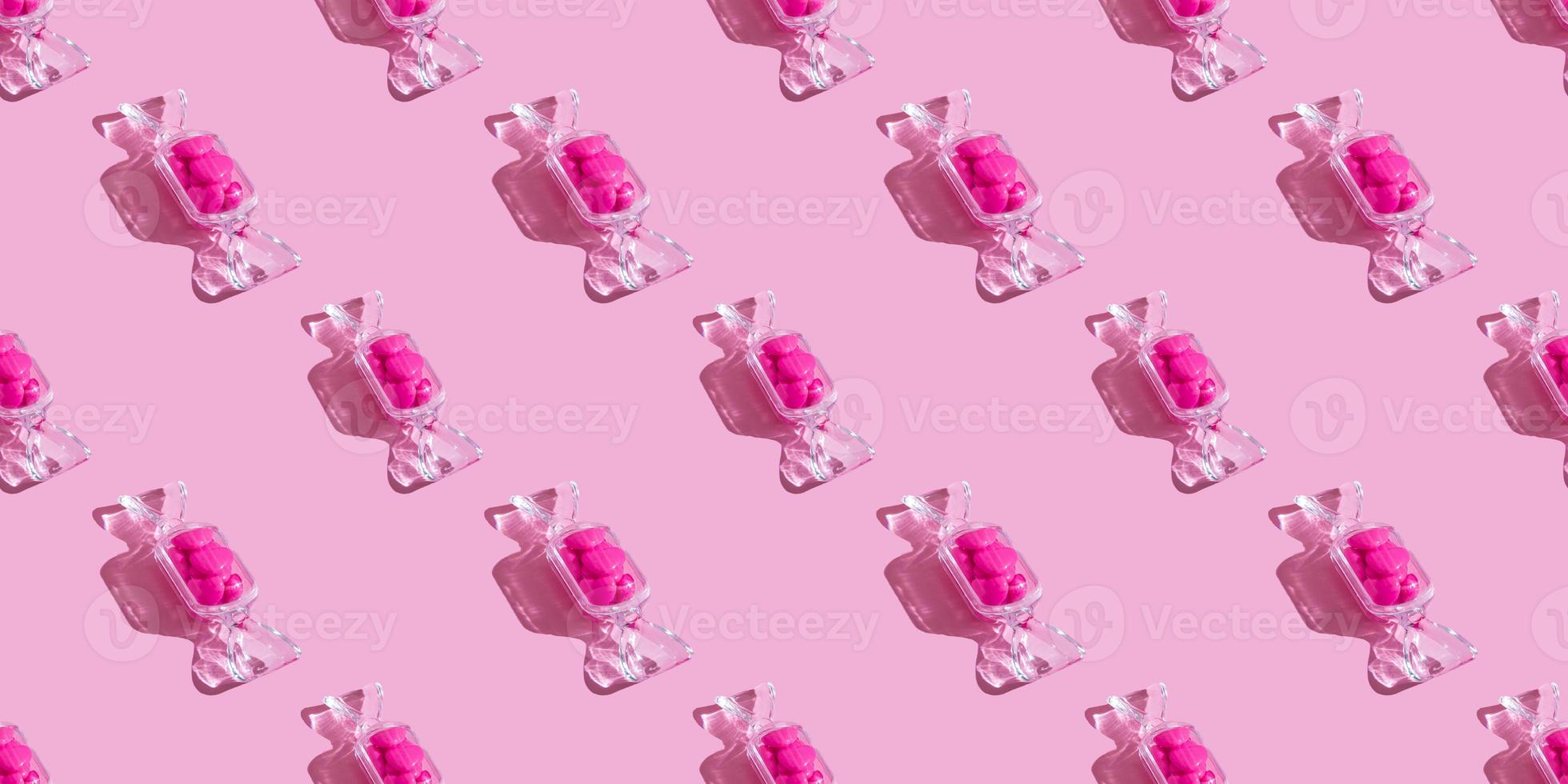 caixa transparente em forma de doce com pirulitos de coração com sombra dura no fundo rosa com espaço de cópia. o conceito de dia dos namorados, dia das mães. bandeira foto