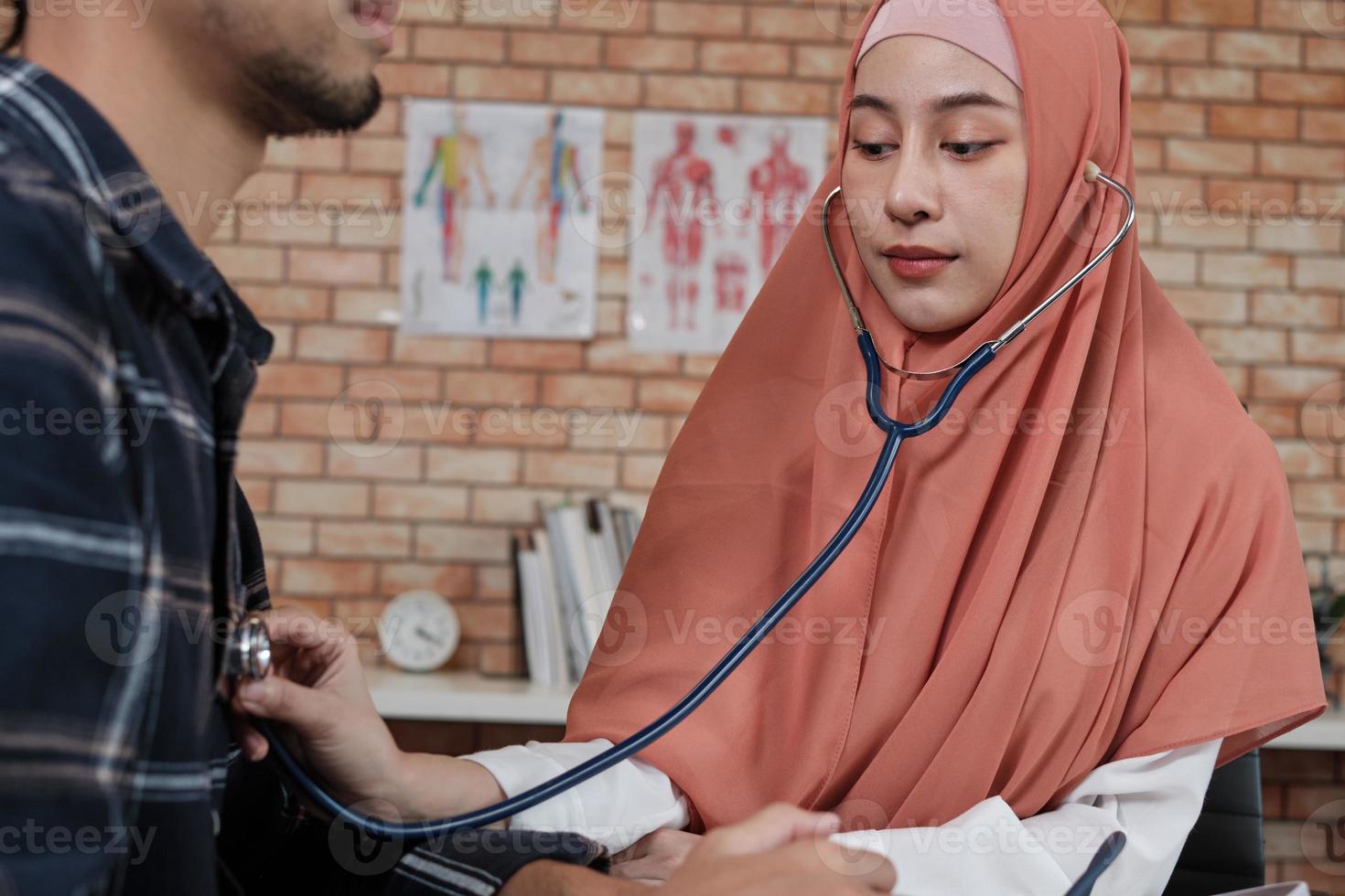 médico jovem bonita é a saúde examinando o paciente do sexo masculino no escritório da clínica do hospital e aconselhando com um sorriso sobre medicamentos. este especialista médico asiático é uma pessoa islâmica que usa um hijab. foto