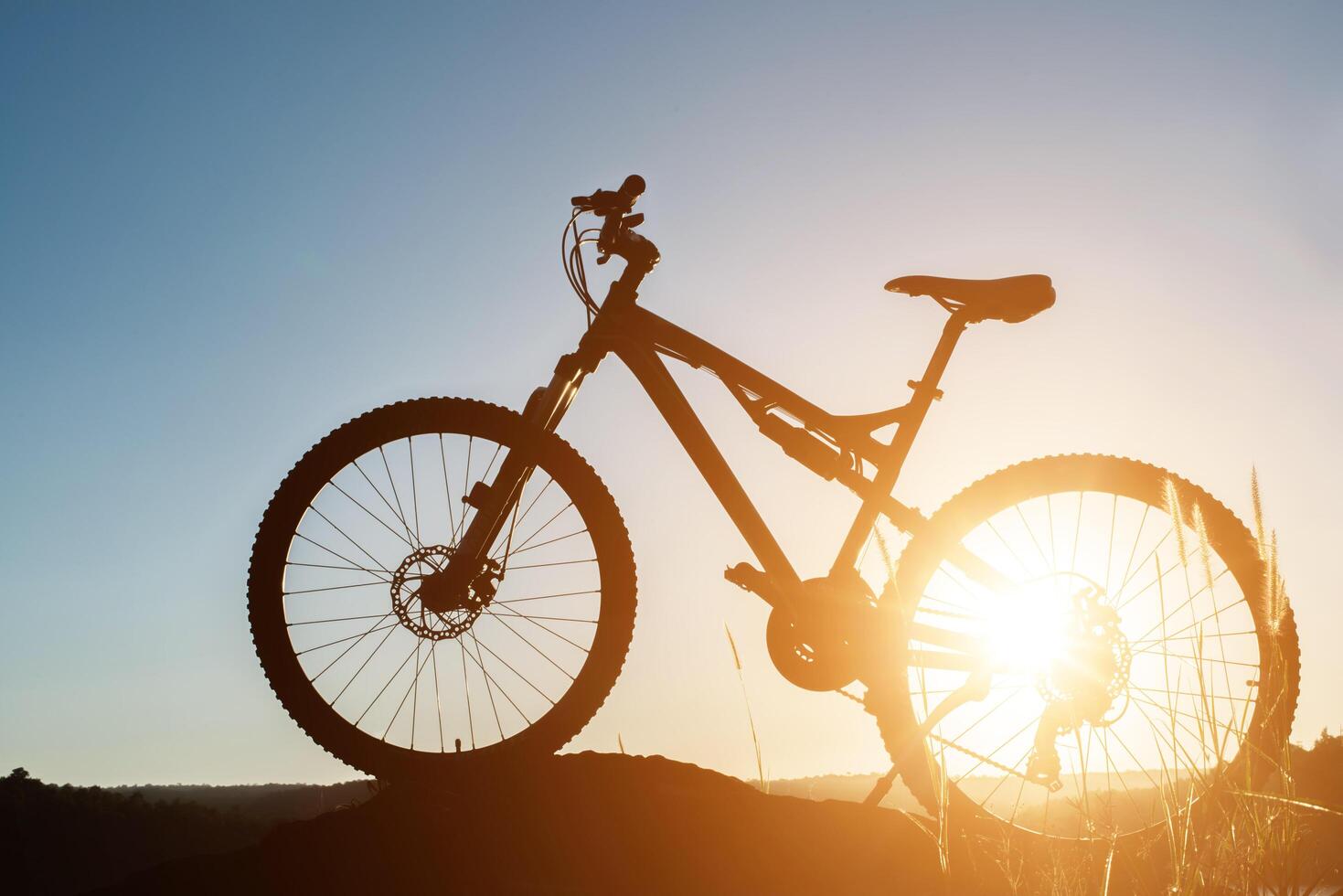 silhueta mountain bike na rocha ao pôr do sol do céu foto